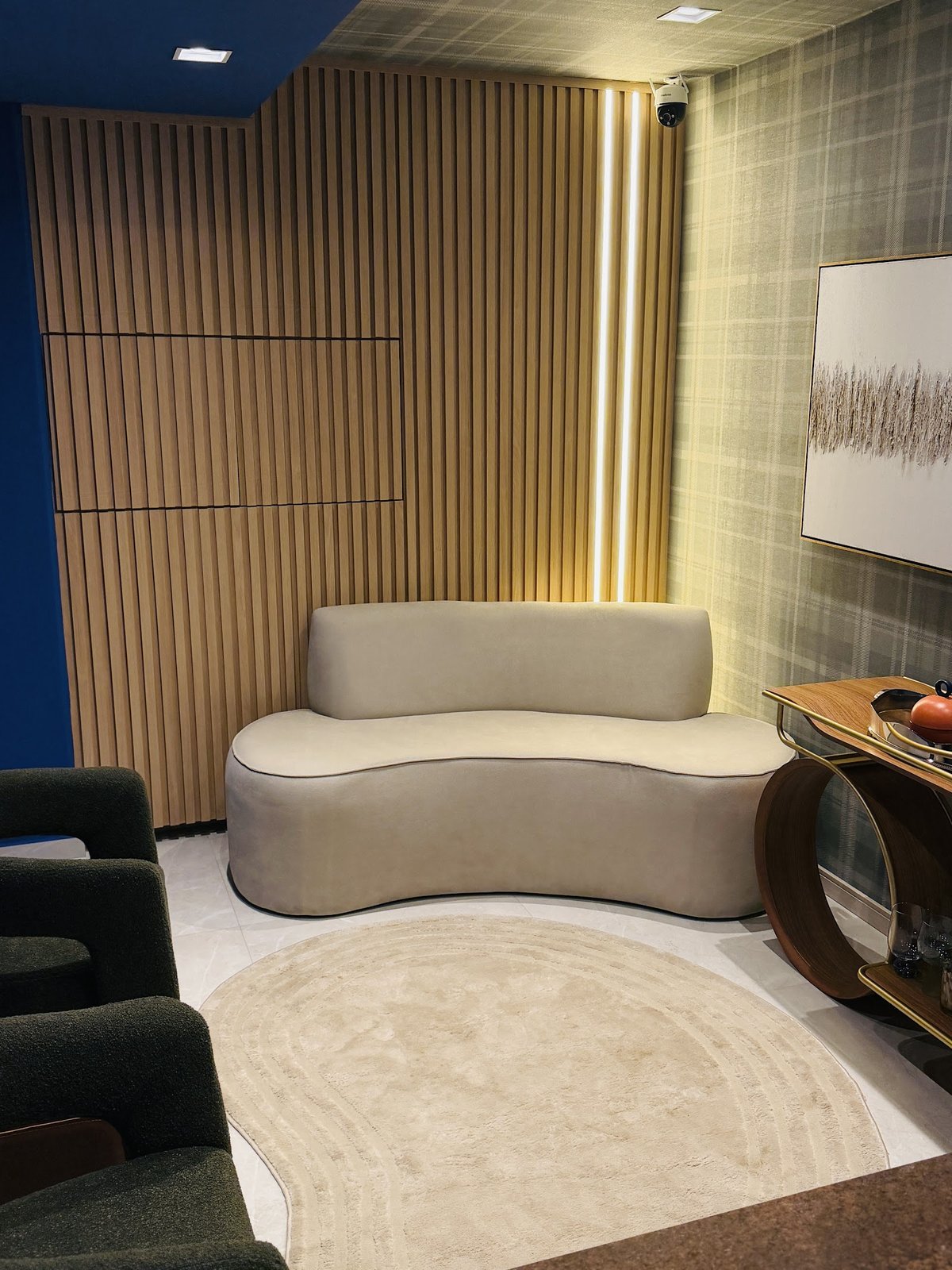 Sala de espera com sofá claro e painel de madeira